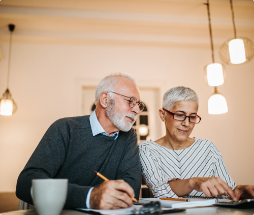 Elderly couple looking at calculator over kitchen table